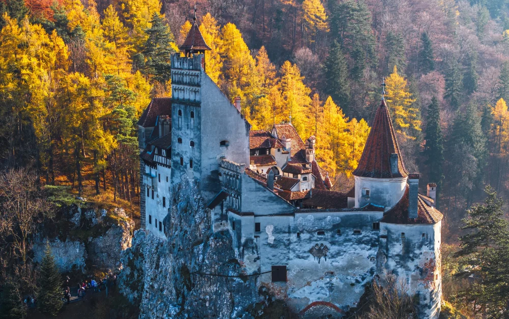 Bran Castle perched on a rocky hilltop above autumn forests in Transylvania, Romania